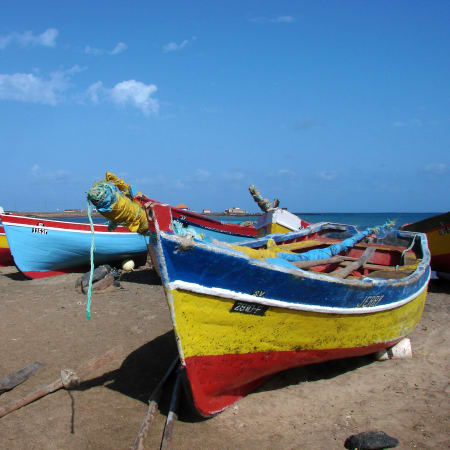 Bateaux de pêche colorés alignés sur la plage de Santiago, île du Cap Vert, avec océan bleu et ciel dégagé