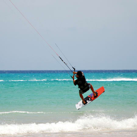 Kitesurfeur en action sur les vagues turquoise de Sotavento avec cerf-volant et planche rouge