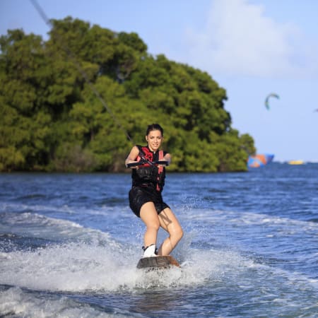 Pratiquant de kitesurf en action sur une plage de Martinique avec voile et mangrove tropicale en arrière-plan