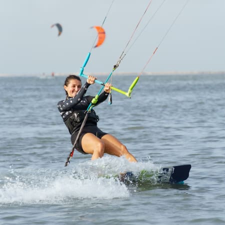 Kitesurfeur autonome naviguant sur l'eau avec cerf-volant orange et planche, séjour liberté 15 jours UCPA