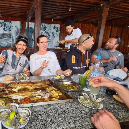 Moniteur et élèves en cours de kitesurf partagent un repas convivial autour de plats traditionnels lors d'une session de perfectionnement