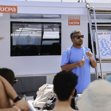Animateur en t-shirt bleu présentant une carte des espèces marines lors d'une excursion Plongée exploration en aquarium géant