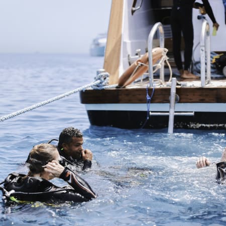 Plongeurs en combinaison équipés de bouteilles d'oxygène en Mer Rouge près d'un bateau de plongée