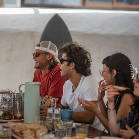 Groupe de windsurfeurs partageant un repas convivial à Costa Teguise avec planche de windsurf en arrière-plan