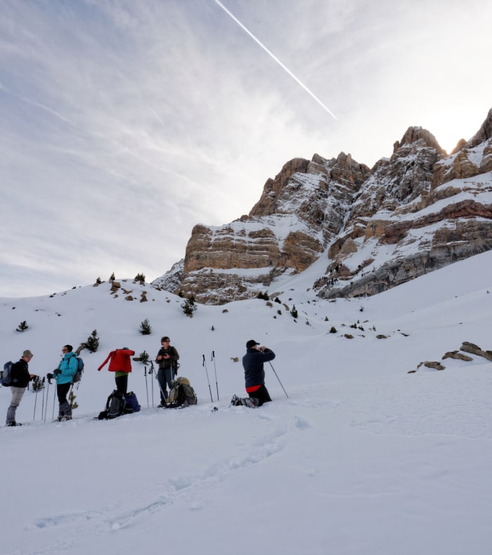 Groupe de randonneurs en raquettes dans les Pyrénées d'Ordesa avec falaises rocheuses enneigées en arrière-plan