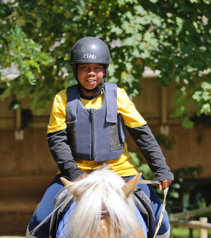 Jeune participant au camp sportif portant un casque de protection et un gilet de sécurité jaune et bleu lors d'activités de plein air