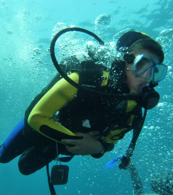 Plongeur en équipement complet explorant les fonds marins avec bouteille d'air et palmes bleues