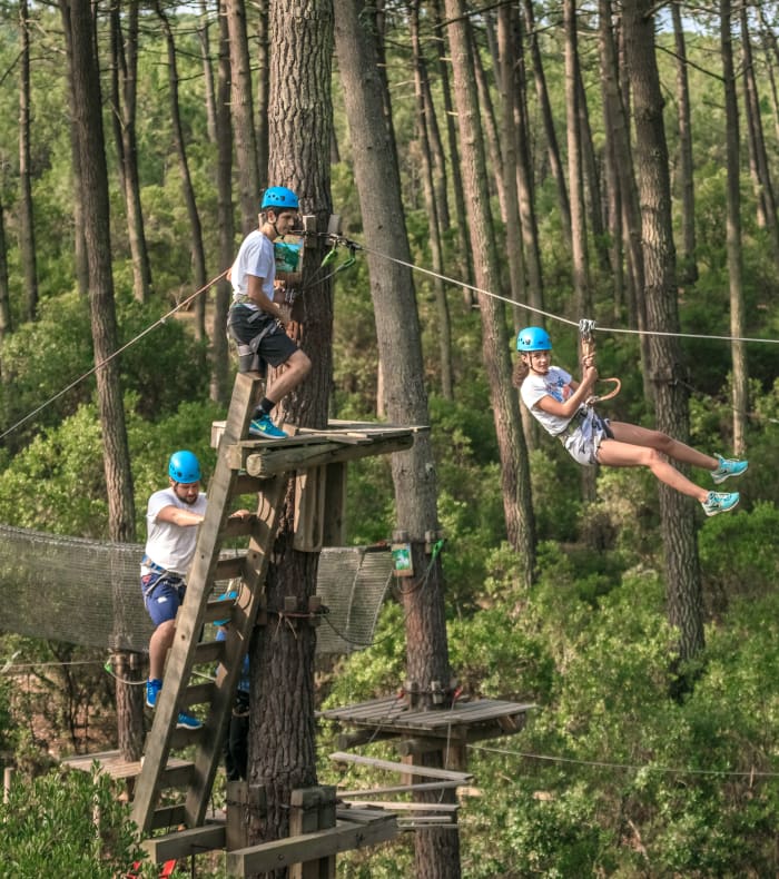 Adolescents en parcours aventure dans les arbres avec tyrolienne et ponts suspendus en forêt, activité du séjour Multi'Sensations