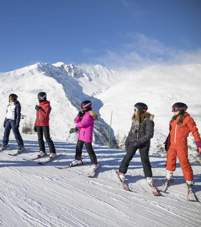 Groupe d'enfants en cours de ski et snowboard à Valloire avec moniteur, montagnes enneigées en arrière-plan