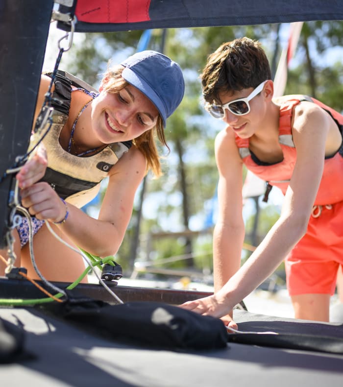 Deux adolescentes souriant lors d'une activité nautique multisports à Bombannes avec voile et équipement de glisse