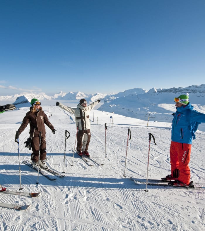 Groupe de skieurs en cours de coaching sur les pistes enneigées du Grand Massif avec vue sur les montagnes alpines
