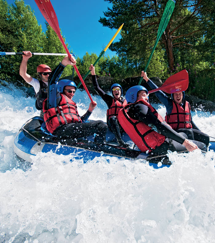 Groupe de participants en rafting sur rapides avec gilets de sauvetage rouges et pagaies colorées aux Hautes Alpes