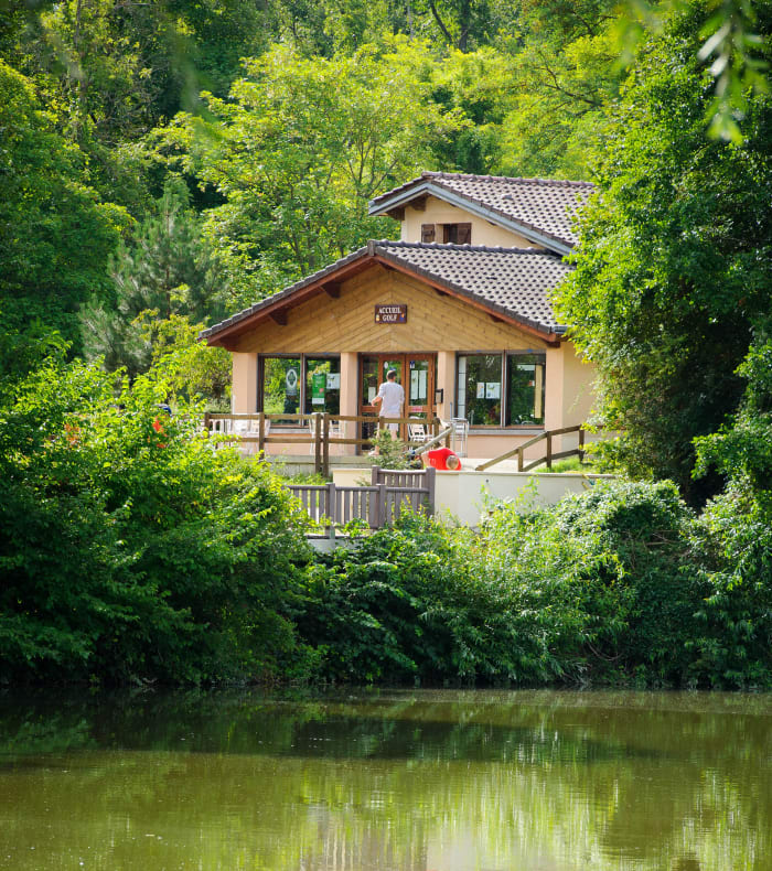 Club-house du Full Golf entouré de végétation verdoyante avec terrasse et accueil pour les golfeurs