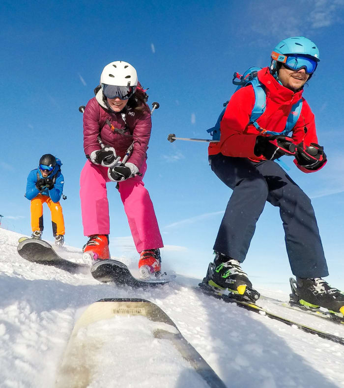 Enfants apprenant à skier en groupe sur pente enneigée avec moniteur en vêtements rouges