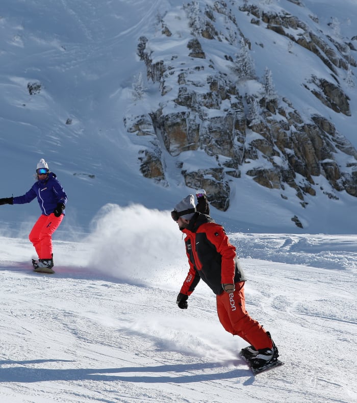 Skieurs en action sur les pentes enneigées des 3 Vallées avec pics rocheux et paysage alpin en arrière-plan