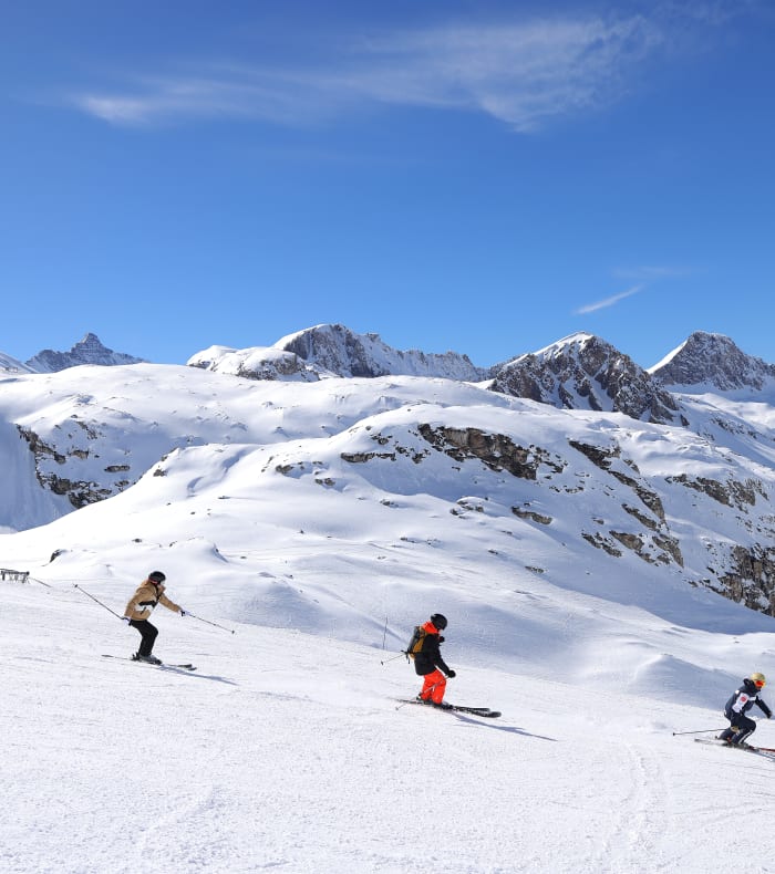 Groupe de jeunes skieurs dégringolant les pentes enneigées de Serre Chevalier avec vue sur les sommets alpins