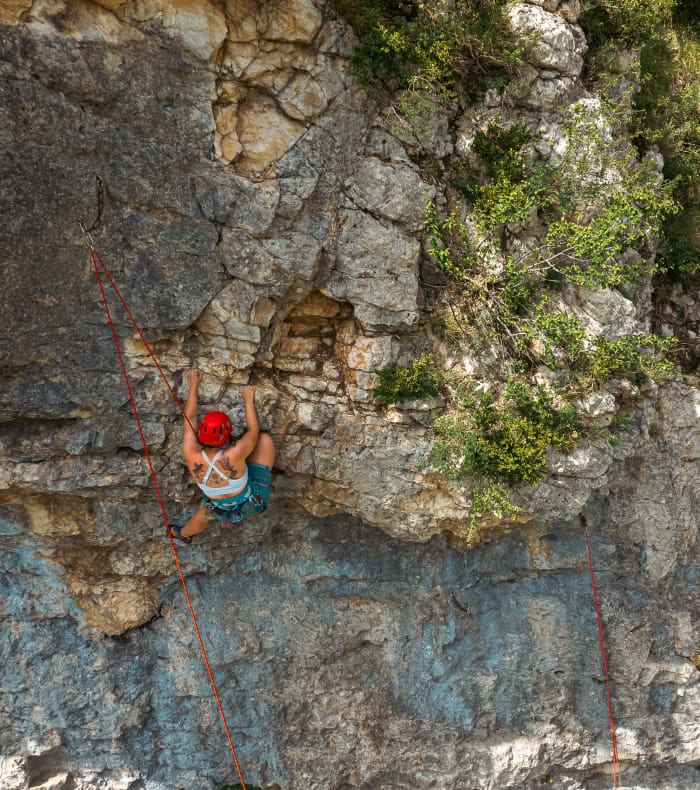 Grimpeur en escalade Evolution sur paroi rocheuse naturelle avec cordes et équipement de sécurité