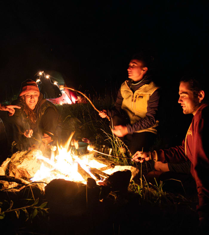 Groupe autour d'un feu de bivouac la nuit lors d'une expédition multisport en montagne