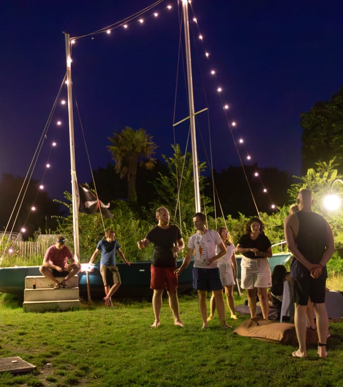 Groupe de participants jouant à des jeux d'équipe autour d'une structure illuminée en soirée à Bénodet-Glénan