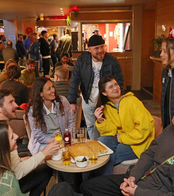 Groupe de skieurs et moniteur partageant un moment convivial dans un refuge alpin après une journée de ski hors-piste aux Arcs