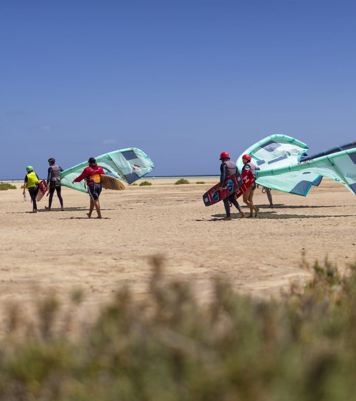 Moniteurs et participants préparant leurs cerfs-volants verts sur la plage pour une session de kitesurf