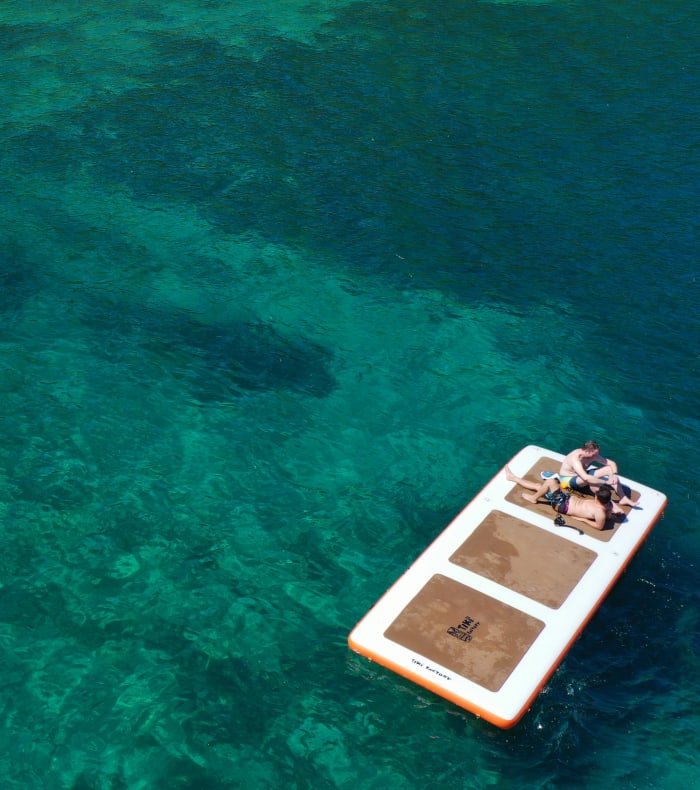 Personne en paddle et baigneur dans les eaux turquoise cristallines de l'Archipel des Saintes