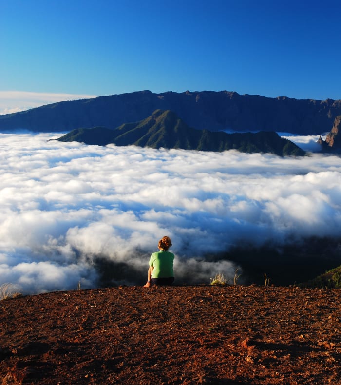 Randonneur en gilet jaune observant les pics volcaniques de Gran Canaria émergeant des nuages