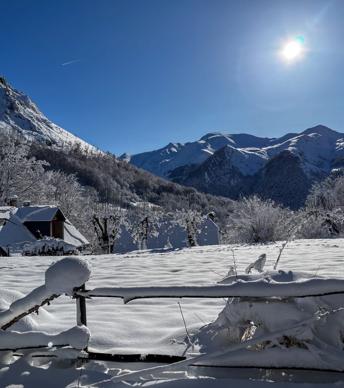 Vallée enneigée des Pyrénées avec chalets en bois, montagnes enneigées et ciel dégagé, cadre idéal pour retraite yoga hivernale