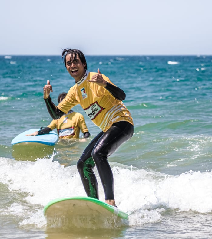 Jeune surfeur en combinaison jaune chevauchant une vague à Montalivet lors de la semaine Sunny Surf 18-30 ans