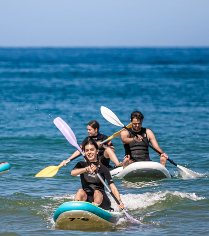 Groupe de participants UCPA en kayak et paddle dans l'océan lors d'une aventure sportive estivale