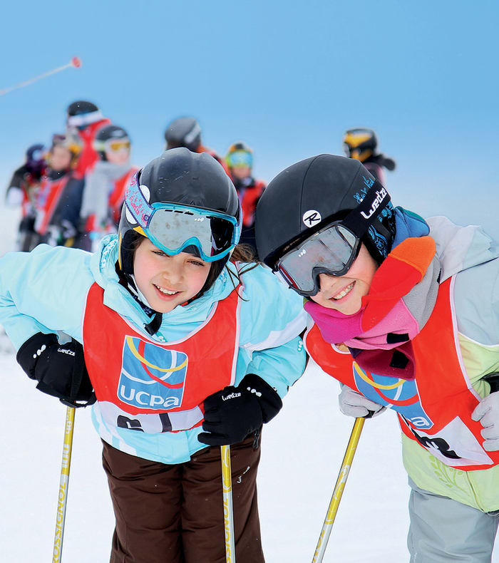 Jeunes enfants skiant en groupe avec moniteurs lors d'un cours de ski débutant à Flaine, portant gilets de sécurité colorés et équipement de ski complet