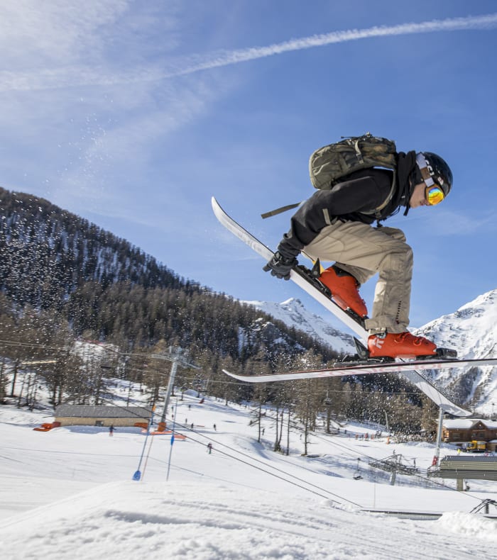 Skieur en vol au-dessus d'un saut en montagne enneigée lors d'une classe nature séjour accompagnant