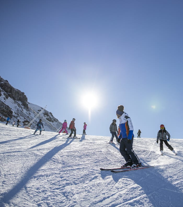 Groupe d'enfants et moniteurs skiant sur les pistes enneigées de Val Cenis sous un ciel bleu ensoleillé