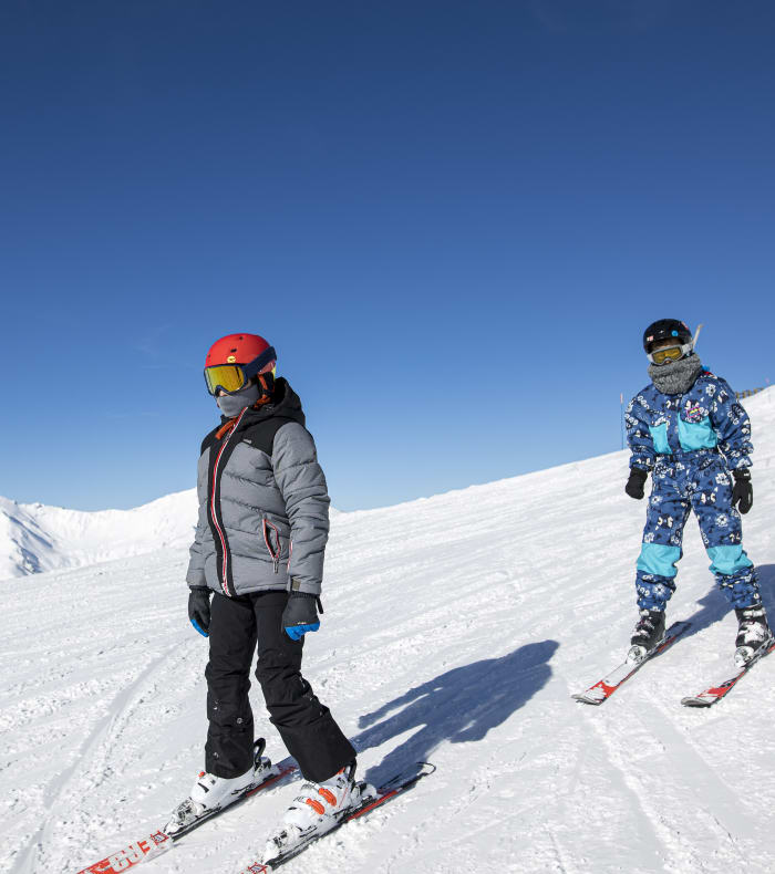 Deux enfants skiant sur les pistes enneigées des Orres avec vue panoramique sur les montagnes des Alpes du Sud