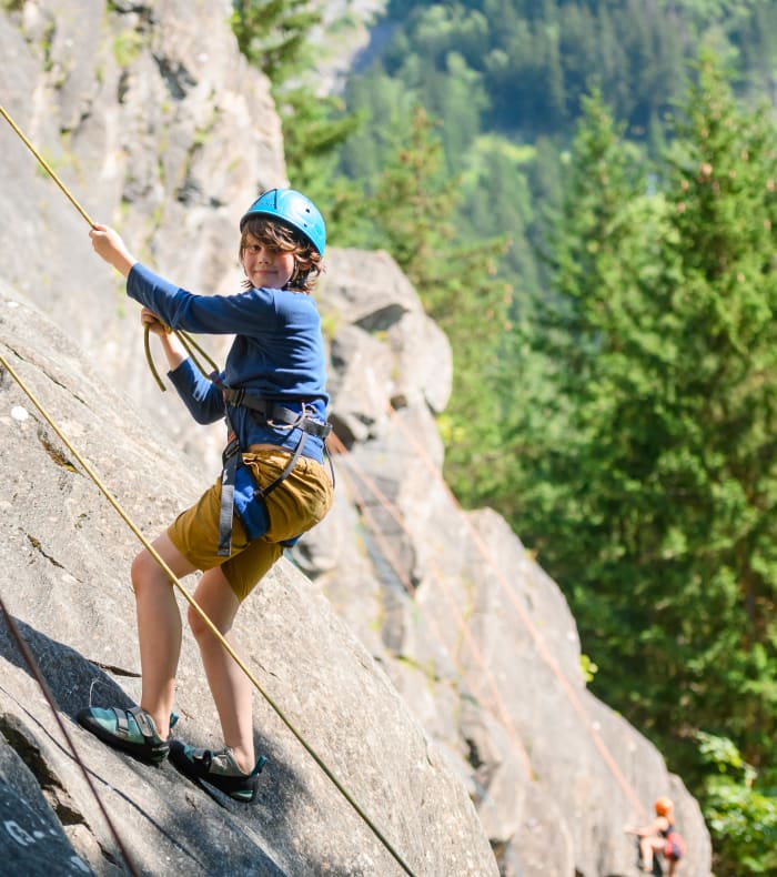 Enfant pratiquant l'escalade en montagne à Valloire avec casque de protection et équipement de sécurité