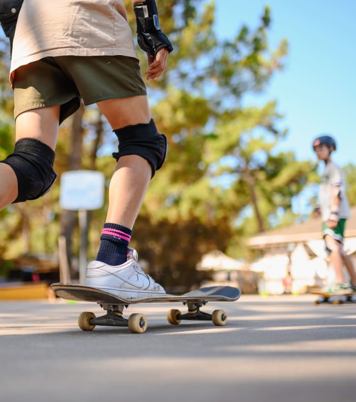 Adolescent en skateboard portant protections aux genoux, pratiquant les sports de glisse en extérieur