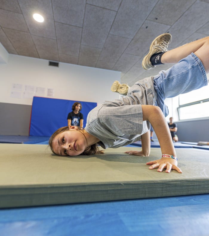 Enfant pratiquant le breaking en salle de danse, en position de freeze sur un tapis de sol