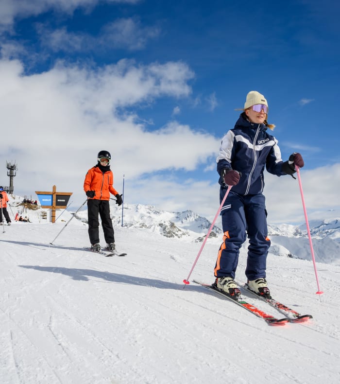 Groupe d'enfants pratiquant le ski alpin sur pente enneigée en montagne avec paysage alpin enneigé en arrière-plan