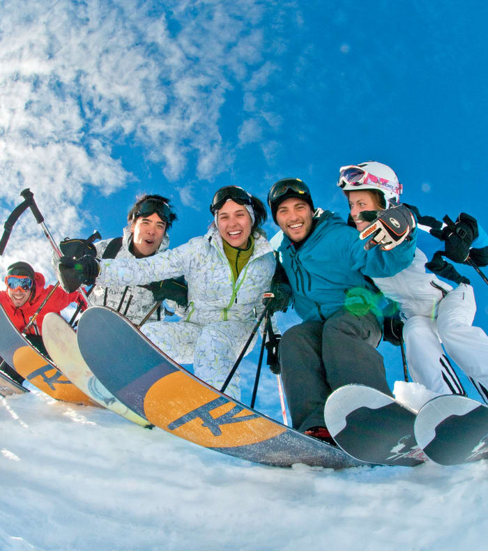 Famille de skieurs posant ensemble dans la neige avec moniteur en séjour ski hors-piste aux Contamines