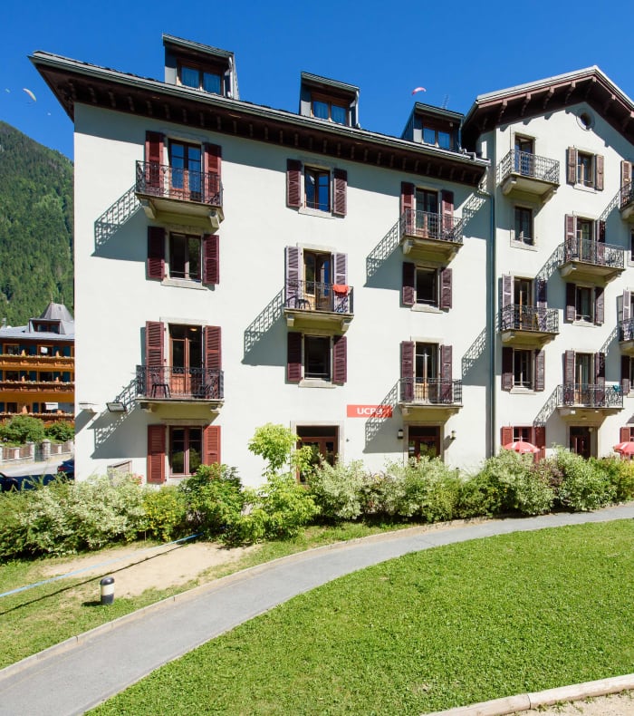 Centre UCPA Chamonix, bâtiment blanc avec balcons colorés entouré de verdure et montagnes boisées