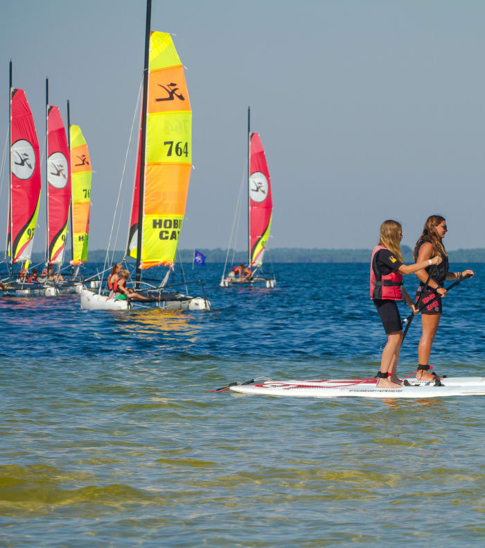 Enfants pratiquant le paddle et la voile sur le lac de Bombannes lors d'une classe de mer sports nautiques