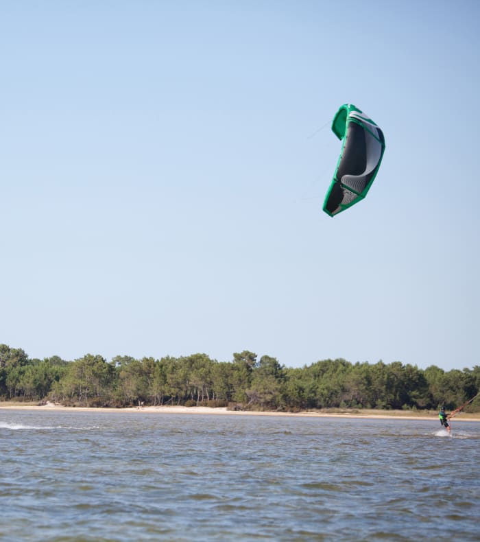Séjour classe de mer au lac du Médoc avec pratiquants de kite et voile sur l'eau et plage en arrière-plan