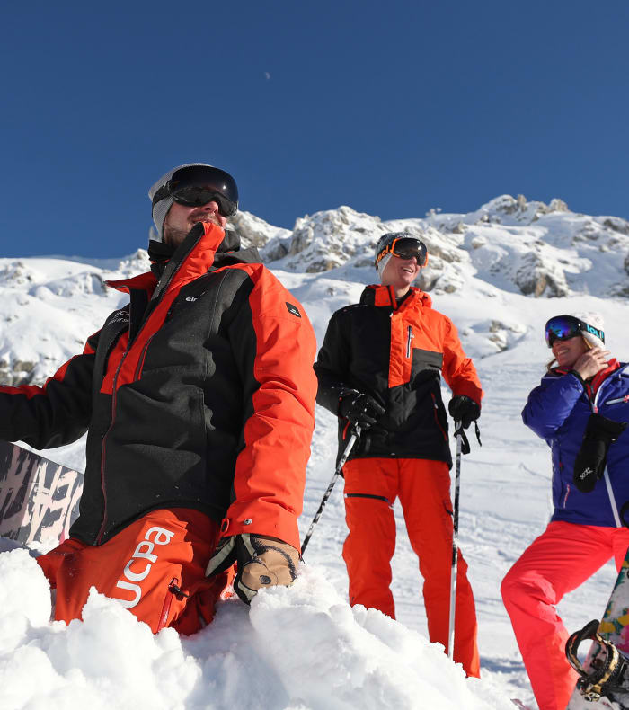 Groupe de skieurs et snowboarders en pause sur les pistes enneigées des Arcs avec vue panoramique sur les sommets alpins