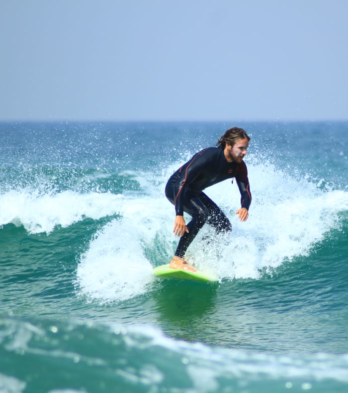 Surfeur en combinaison noire chevauchant une vague en Bretagne lors d'un stage de surf progressant