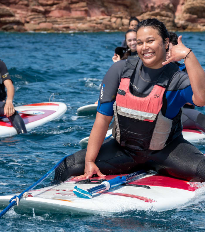 Jeune femme souriante en gilet de sauvetage sur stand-up paddle en mer avec d'autres participants lors d'une séance de sports nautiques à Sanary-sur-Mer
