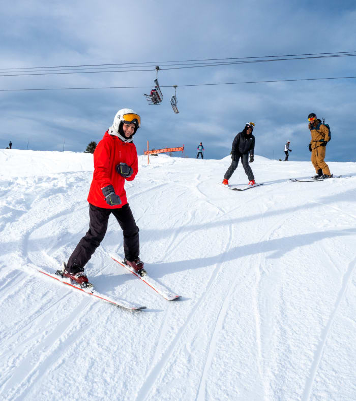 Trois skieurs débutants apprenant le ski sur piste enneigée face aux montagnes alpines enneigées à La Plagne