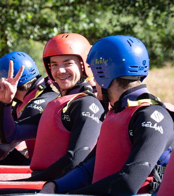Trois participants souriants en équipement de canyoning aux Gorges de l'Allier avec casques et gilets de sauvetage