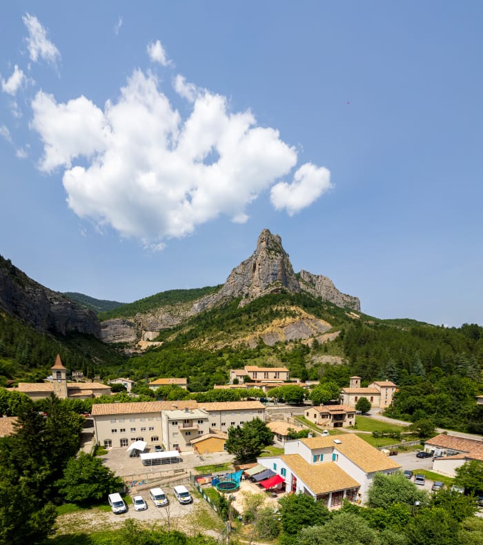 Classe Nature Break 11-18 ans : paysage montagneux avec pic rocheux dominant et forêts verdoyantes sous ciel bleu
