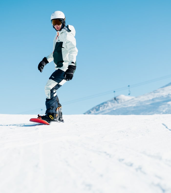 Snowboarder avec équipement Happy Winter sur les pentes enneigées de Val d'Isère, montagnes alpines en arrière-plan