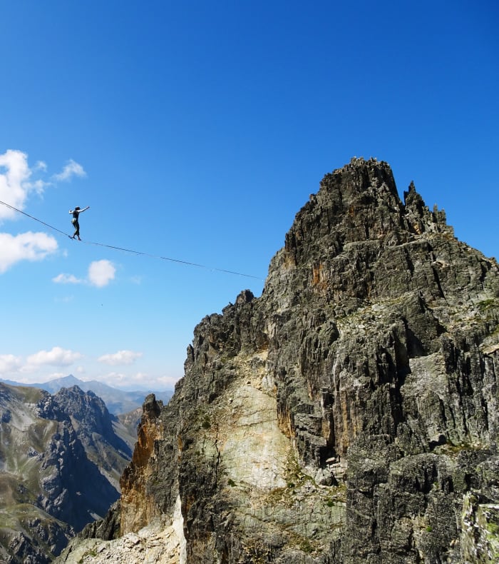 Pratiquant de highline traversant une ligne tendue entre les falaises calcaires d'Orpierre avec vue panoramique sur la vallée alpine